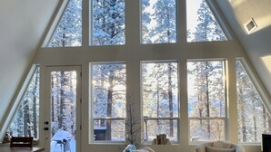 Een ruime loft met hoge plafonds en grote ramen, met uitzicht op een besneeuwd bos.
