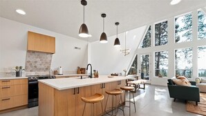 Een moderne keuken met een centraal eiland, barstoelen en hanglampen.