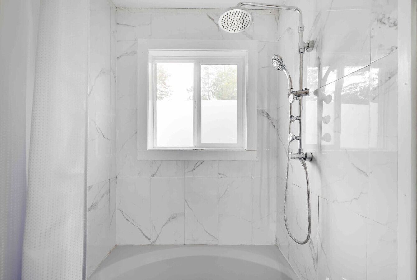 Une salle de bain avec une baignoire, une douche et une fenêtre.
