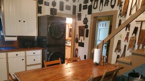 Eine Küche mit Holztisch und -stühlen, einer Waschmaschine und diversen Küchenutensilien an der Wand.