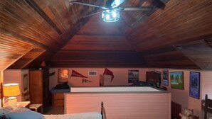 Ein gemütliches Schlafzimmer im Dachgeschoss mit schrägen Wänden, einem Bett, einem Schreibtisch und einem Stuhl.
