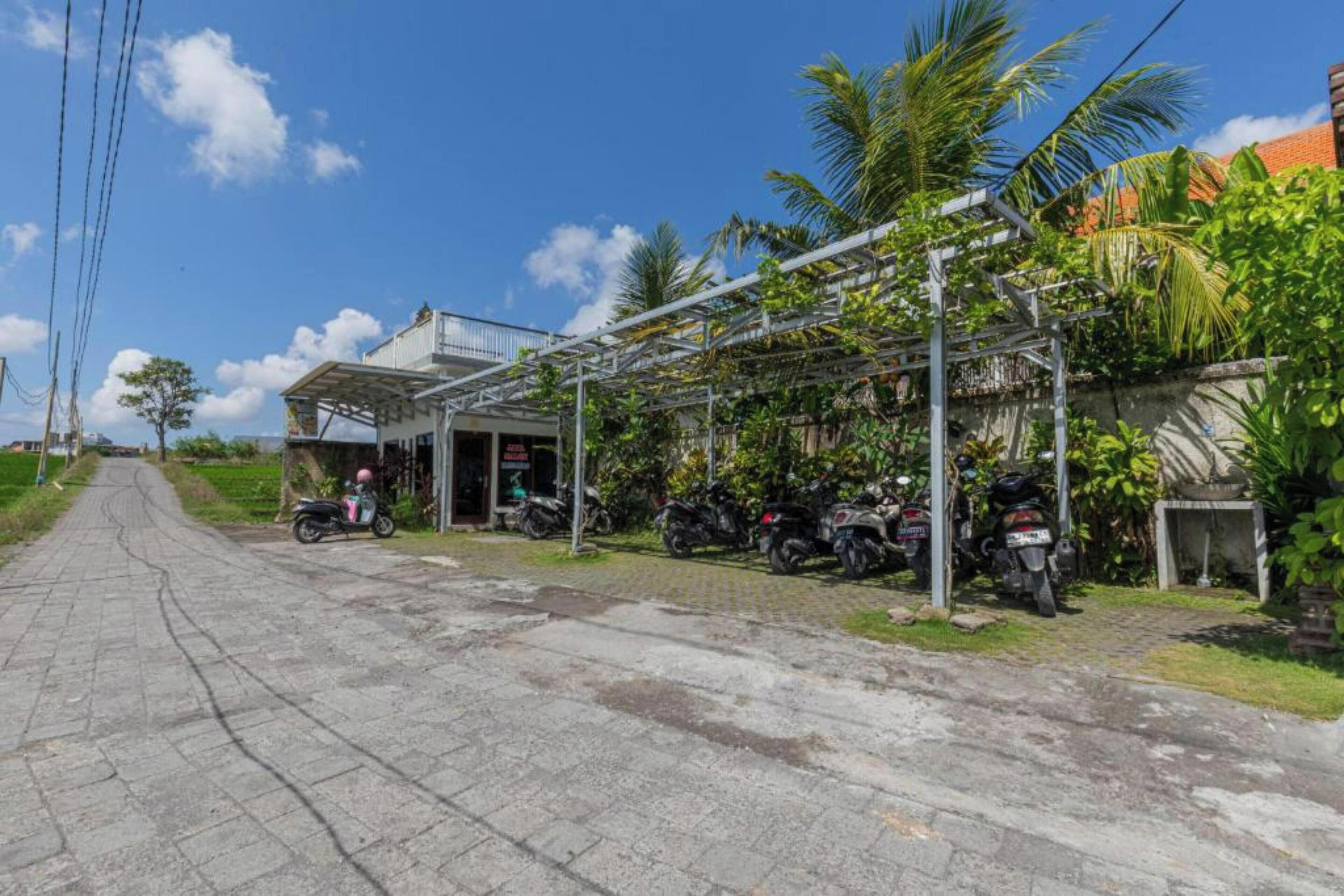 A paved road leading to a building with a covered porch area.