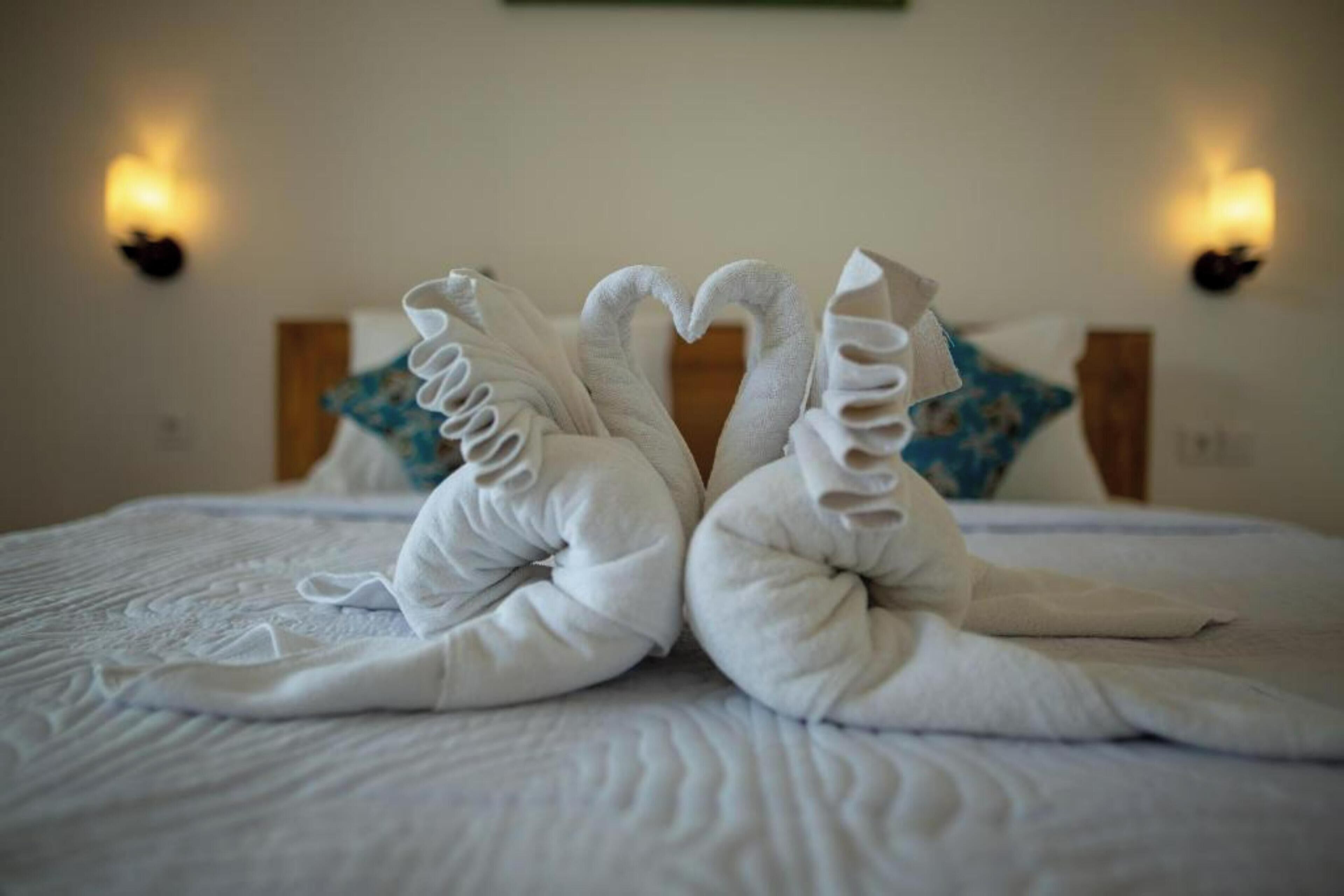 Ein Bett mit zwei Handtüchern, die als Schwanenpaar angeordnet sind.