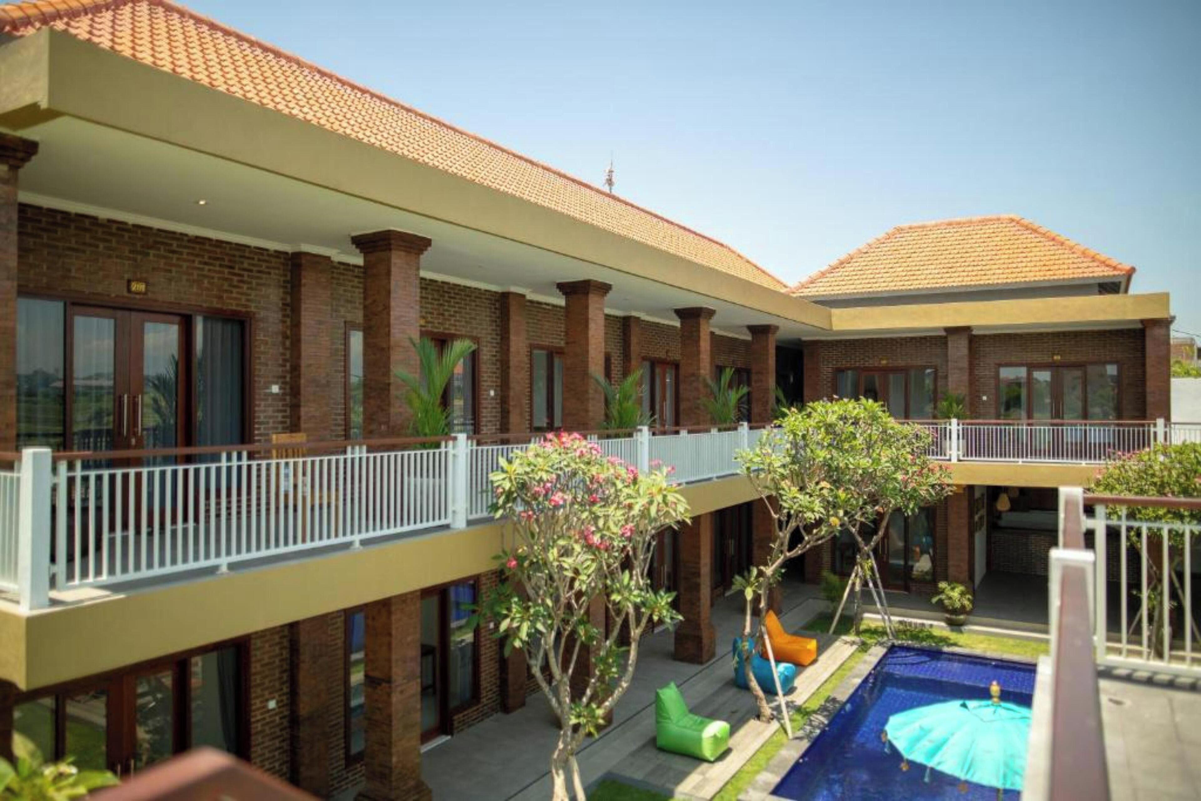A two-story building with a swimming pool, outdoor seating, and a covered patio area.