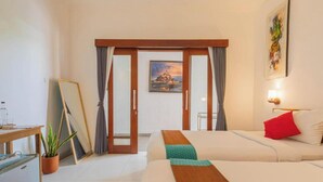 Una habitación de hotel con dos camas, un escritorio, una planta en maceta y un cuadro en la pared.