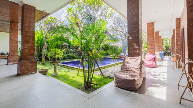 Amplio espacio interior con un gran ventanal, una pequeña piscina y una zona de estar con un sillón de saco.