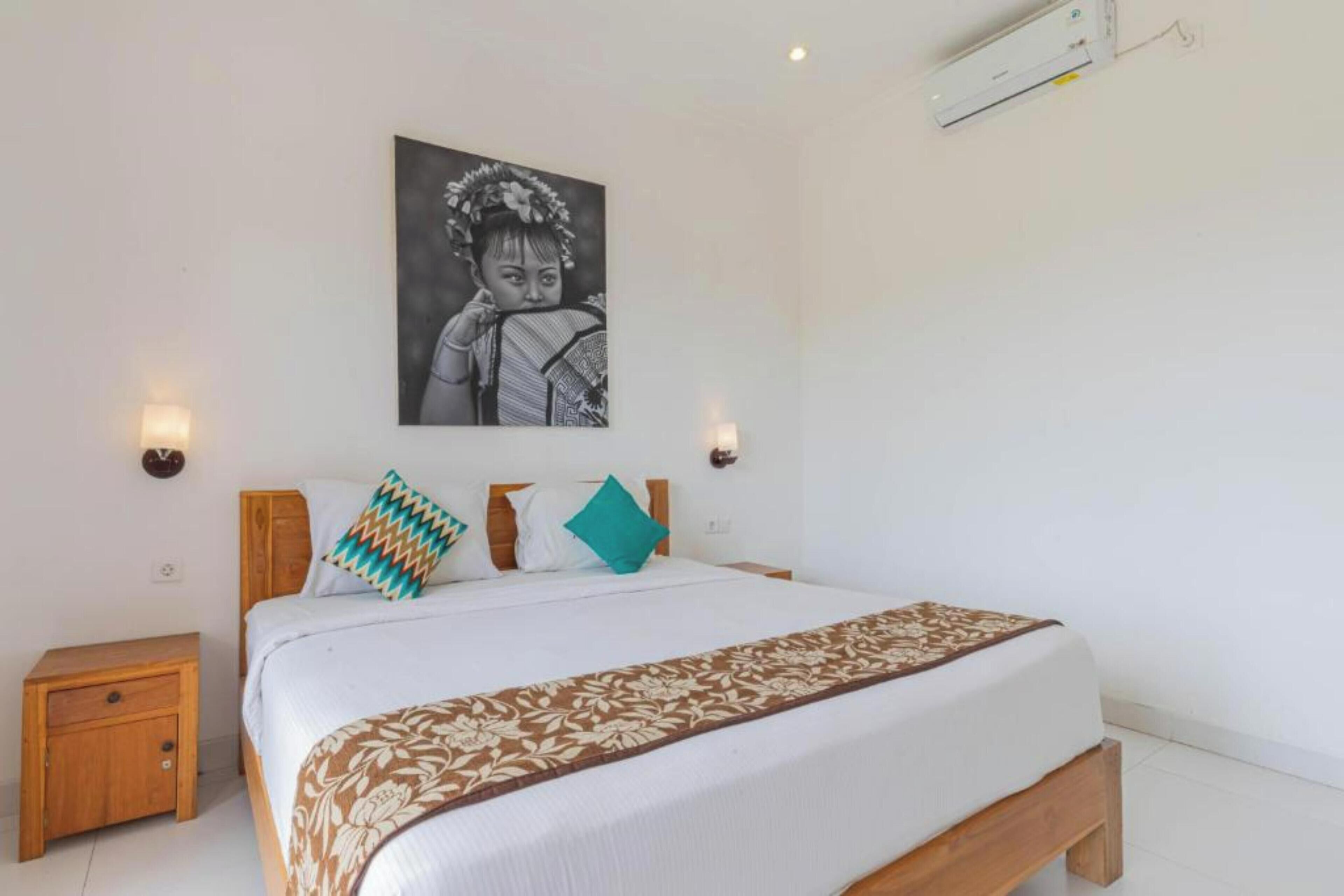 Een slaapkamer met een bed, nachtkastjes, wandlampen en een kunstwerk aan de muur.