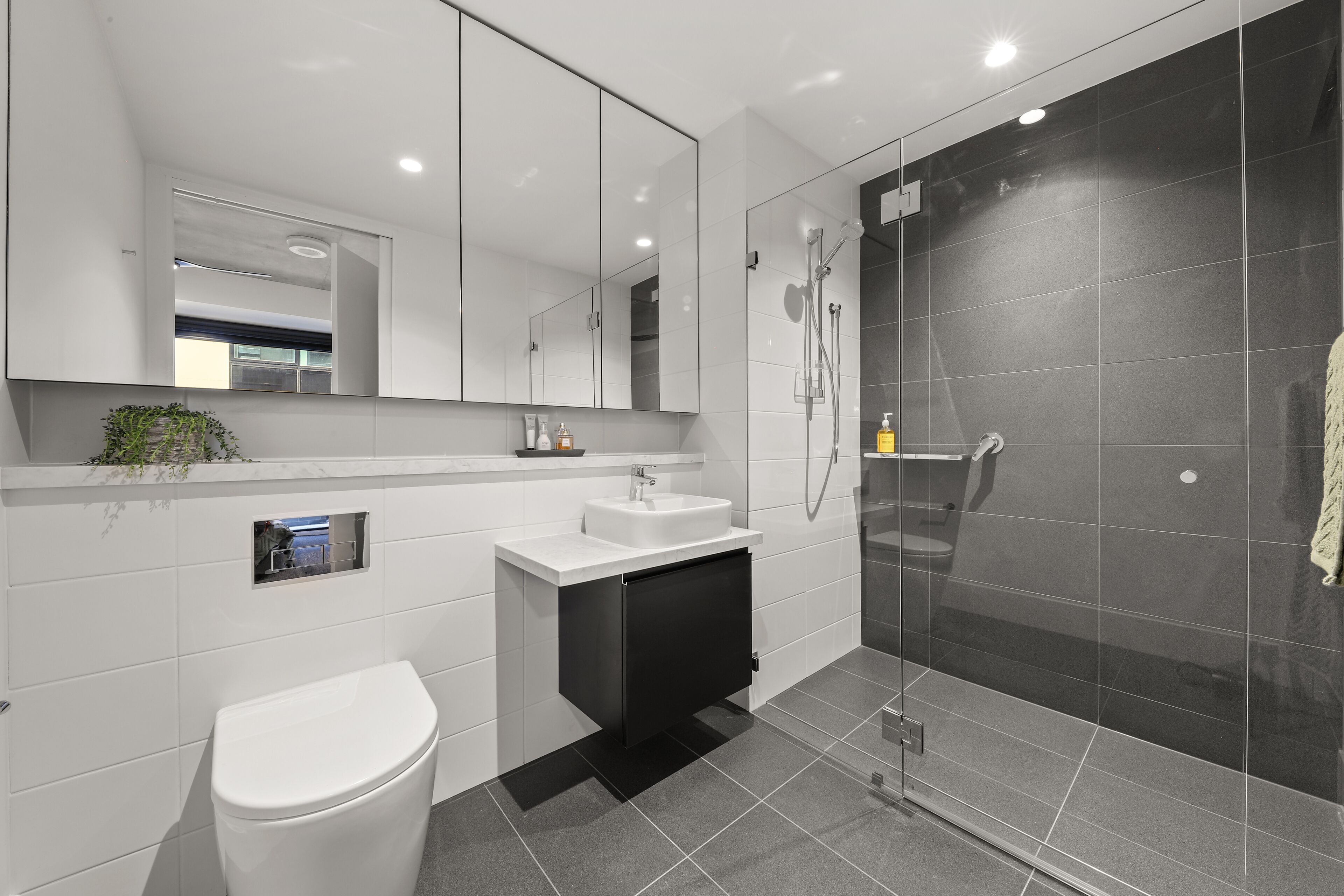 Een moderne badkamer met toilet, wastafel en douche.