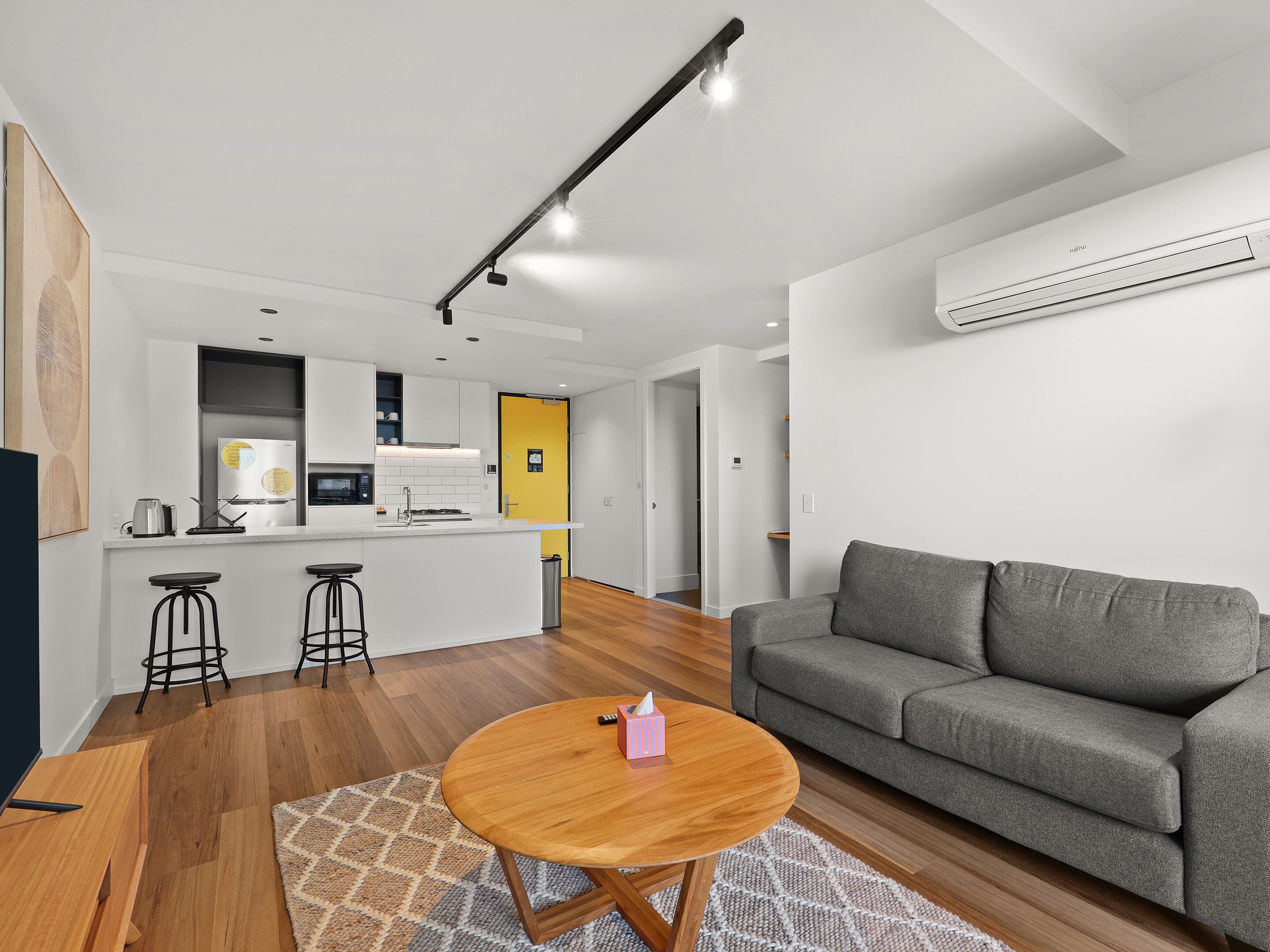 A modern living space with a kitchen, a dining area, and a gray sofa.