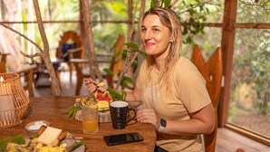 A person seated at a wooden table with breakfast items, a smartphone, and a mug. - Awaken Yoga Eco Resort in Amazon jungle (Indiana)