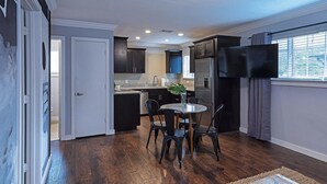 Una cocina moderna con armarios oscuros, un refrigerador de acero inoxidable y un televisor de pantalla plana montado en la pared.