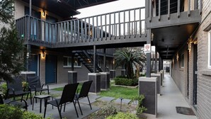 Un bâtiment moderne doté d’un espace extérieur couvert avec des sièges, d’un escalier et d’un panneau indiquant qu’il est interdit de fumer.