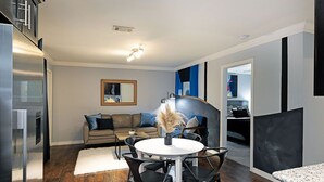 A modern living room with a dining area, a sofa, and a coffee table. - 2BR The TMC Flats 15! Hermann Park! Zoo! (Houston)