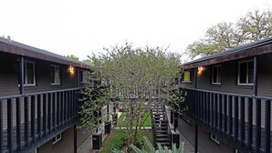 A courtyard with two-story buildings, a central staircase, and a small garden area. - 2BR The TMC Flats 15! Hermann Park! Zoo! (Houston)