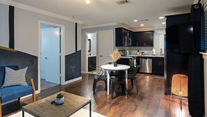 A modern kitchen with dark cabinets, a stainless steel refrigerator, and a dining area with a round table and chairs. - 2BR The TMC Flats 15! Hermann Park! Zoo! (Houston)