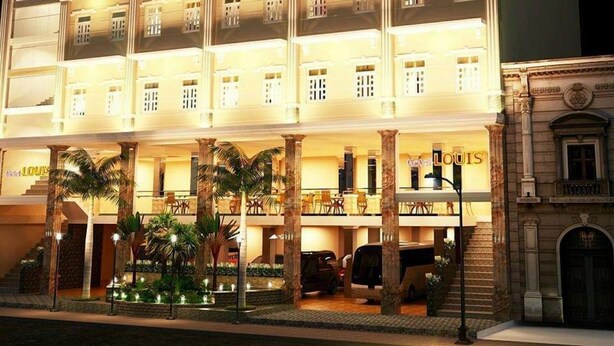 Ein mehrstöckiges Hotel mit einem prunkvollen Eingang, Palmen und einer gut beleuchteten Fassade.