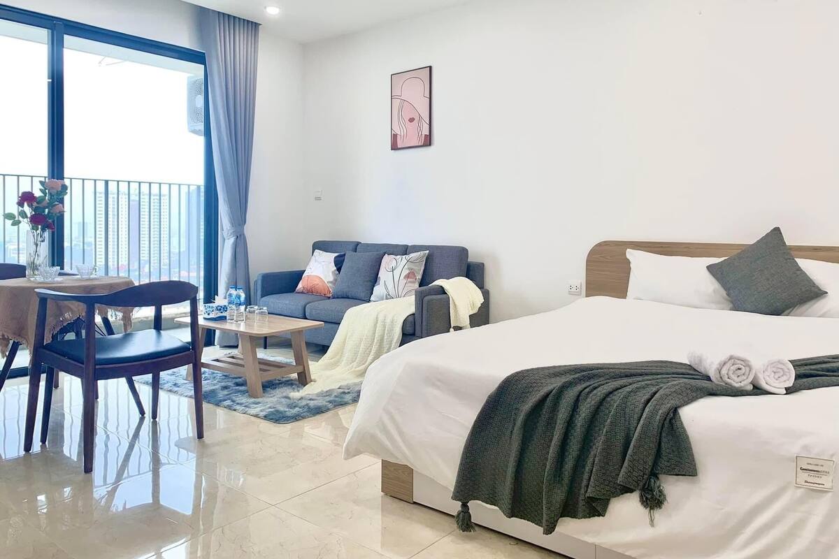 Une chambre d’hôtel moderne équipée d’un lit, d’un canapé, d’une table à manger et d’un balcon offrant une vue sur la ville.