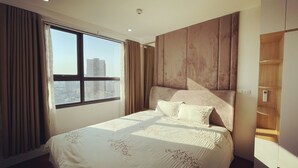 A modern hotel room with a large bed, a city view, and a wooden wardrobe. - Vinhomes D'Capitale Residence - CitiHome (Hanoi)