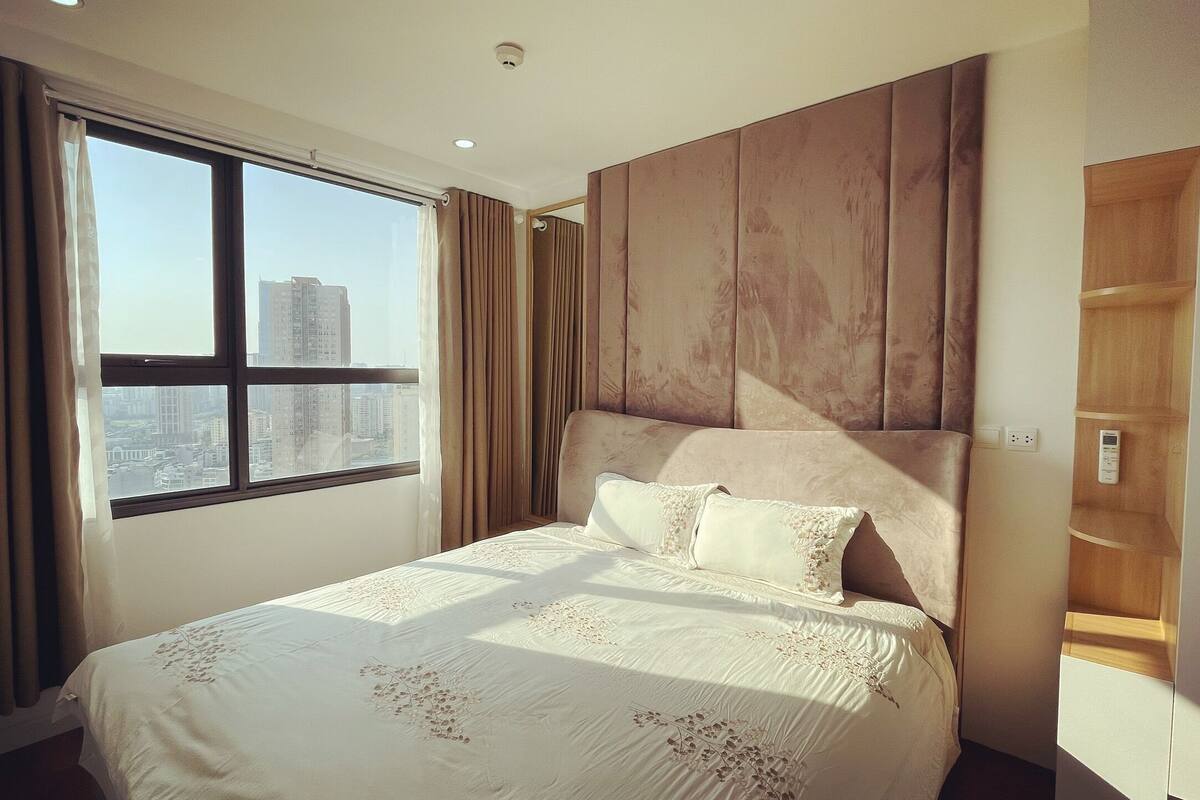 Une chambre d’hôtel moderne avec un grand lit, une vue sur la ville et une armoire en bois.