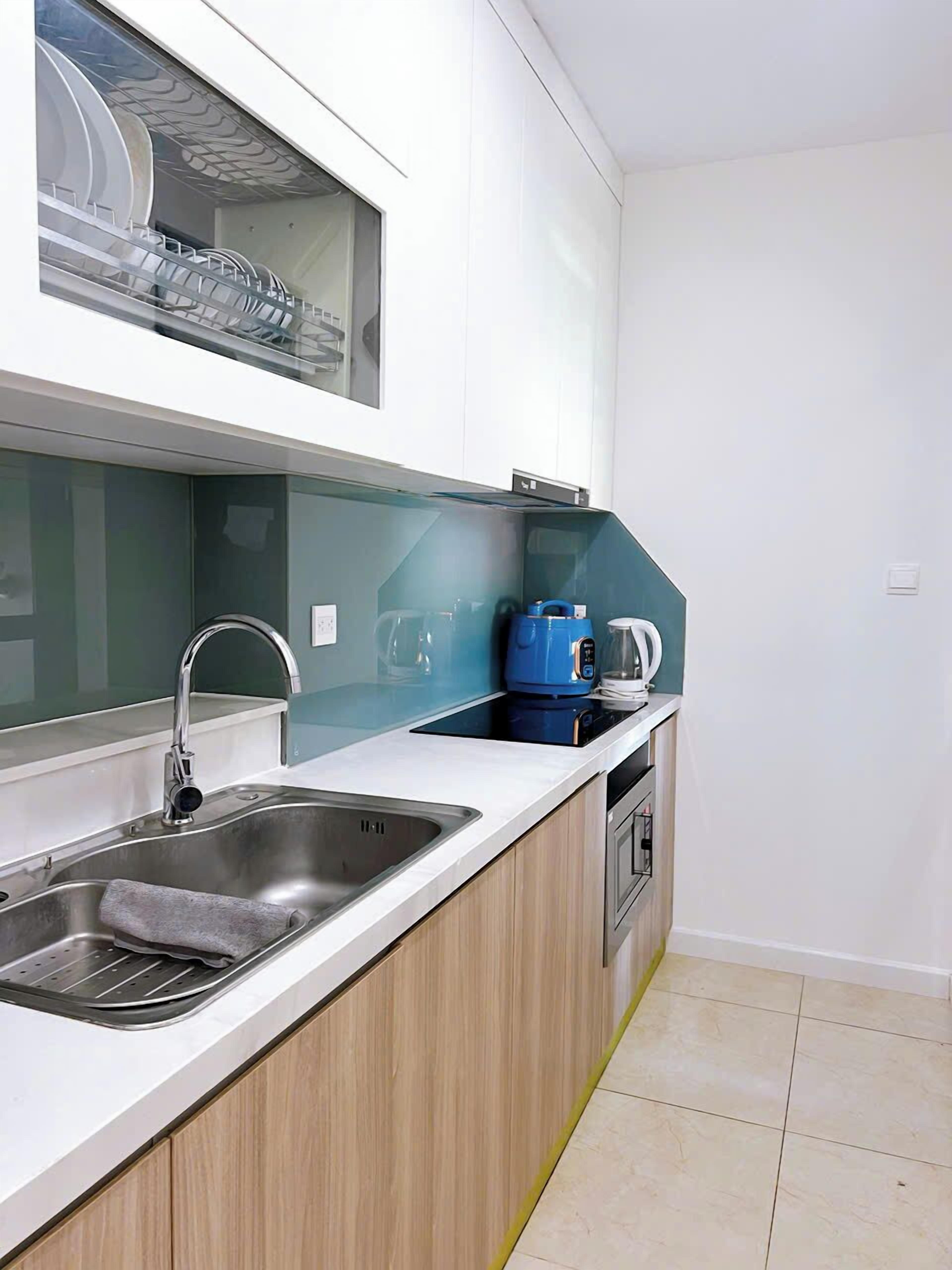 A modern kitchen with a stainless steel sink, a built-in oven, and a microwave.