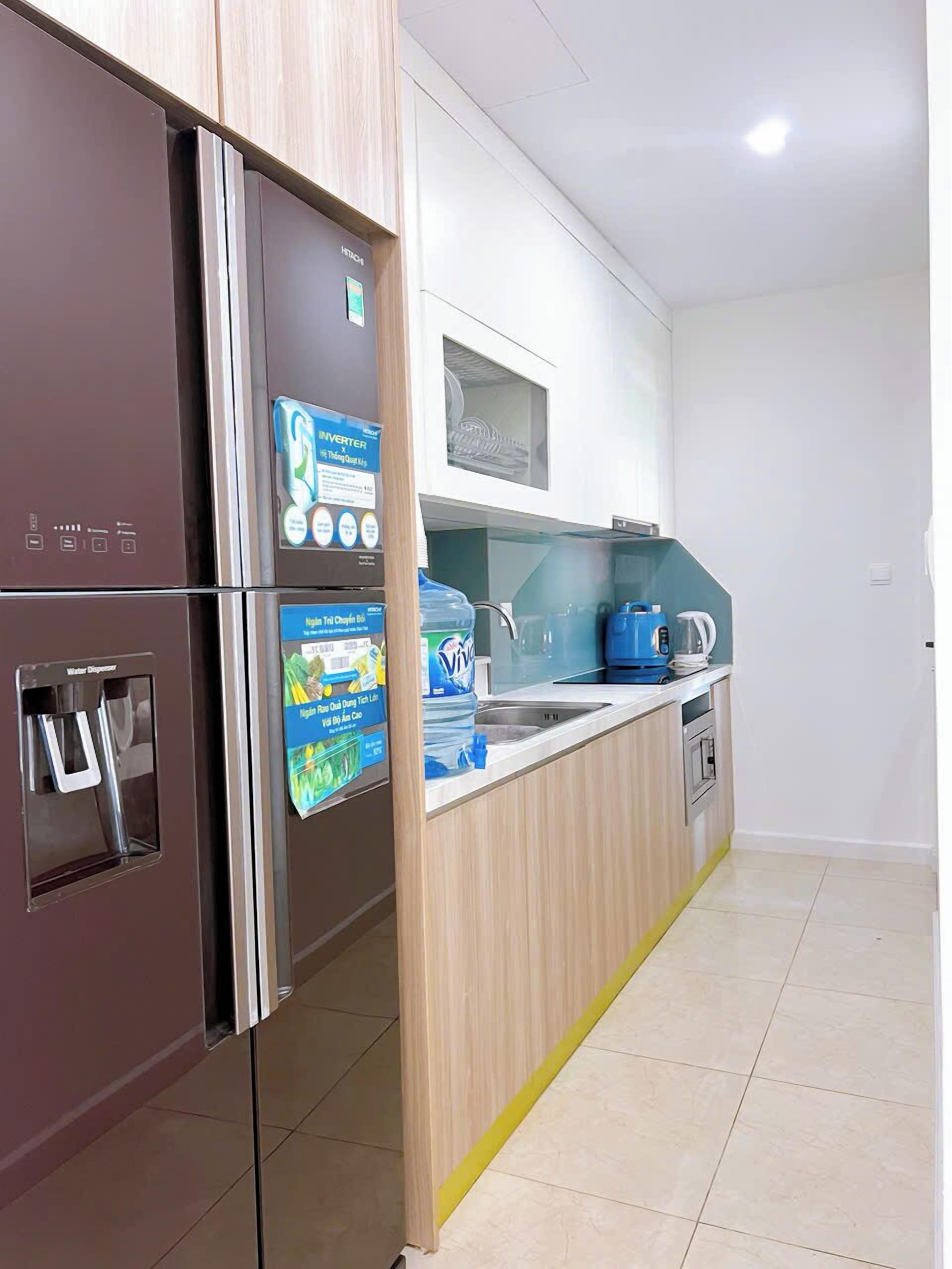 Una cocina moderna equipada con refrigerador, dispensador de agua, microondas y tetera.