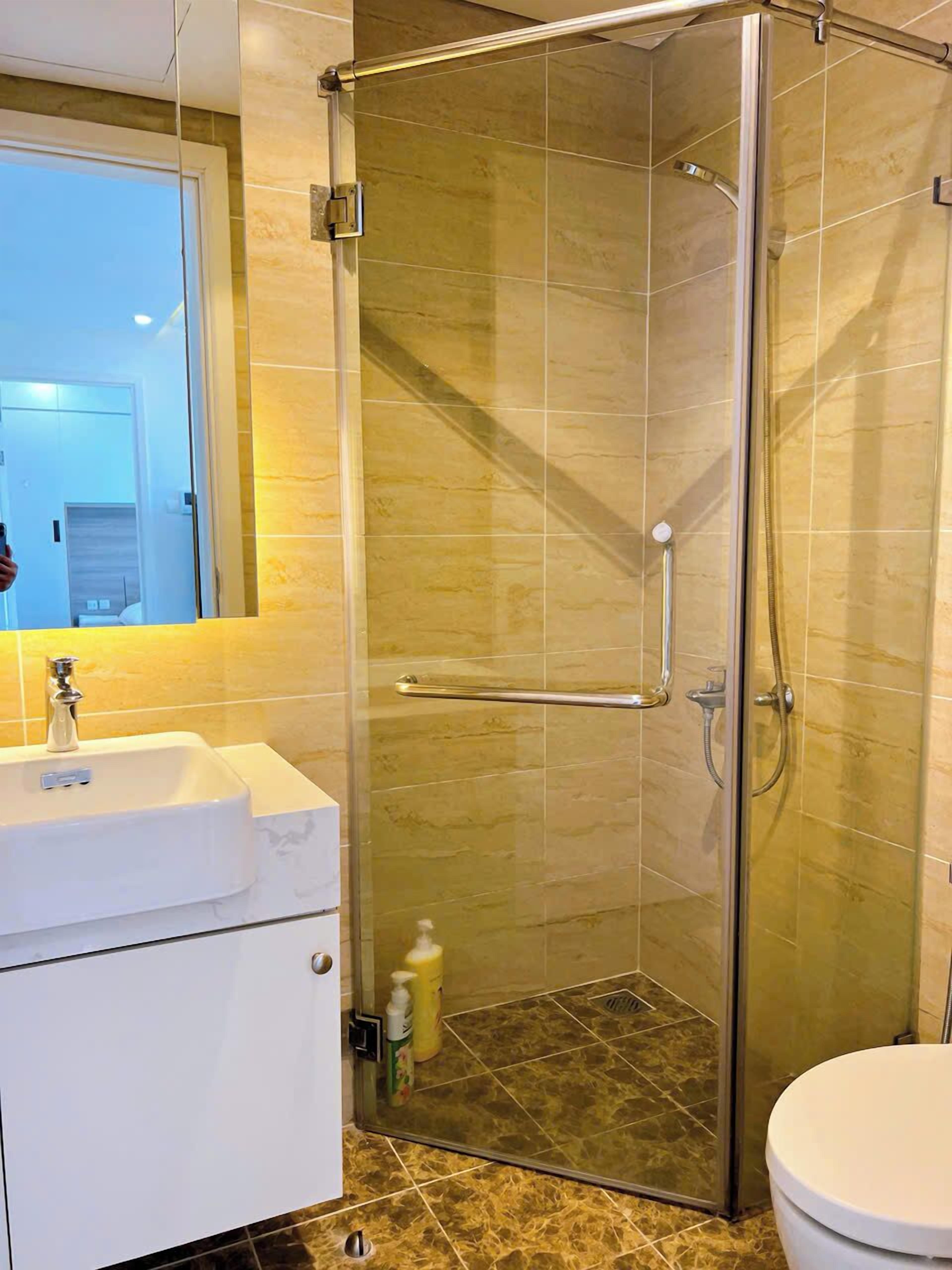 Une salle de bain avec une douche à parois de verre, un lavabo blanc et des toilettes.