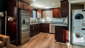 A modern kitchen with dark wooden cabinets, stainless steel appliances, and a built-in washer and dryer.