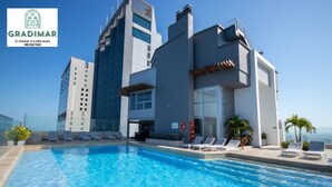 A modern hotel with a rooftop pool, lounge chairs, and a view of the city skyline. - Murano Elite Piso 25 (Cartagena de Indias)