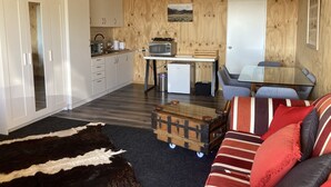 A compact living space with a kitchenette, a sofa, a small table, and a television.