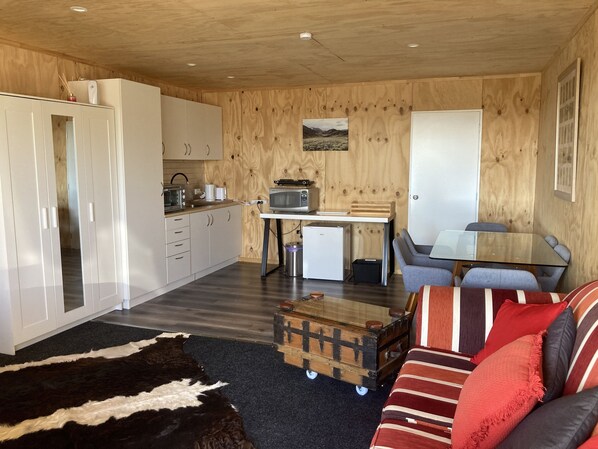 A compact living space with a kitchenette, a sofa, a small table, and a television.