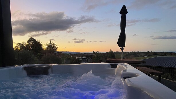 A hot tub with a view of a sunset and distant landscape.