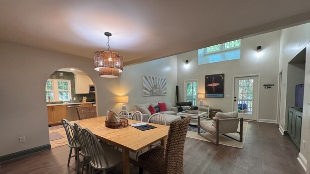 A spacious living area with a dining table, chairs, a sofa, and a kitchen in the background.