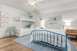 A bedroom with a bunk bed, a single bed, a desk, and a chair.