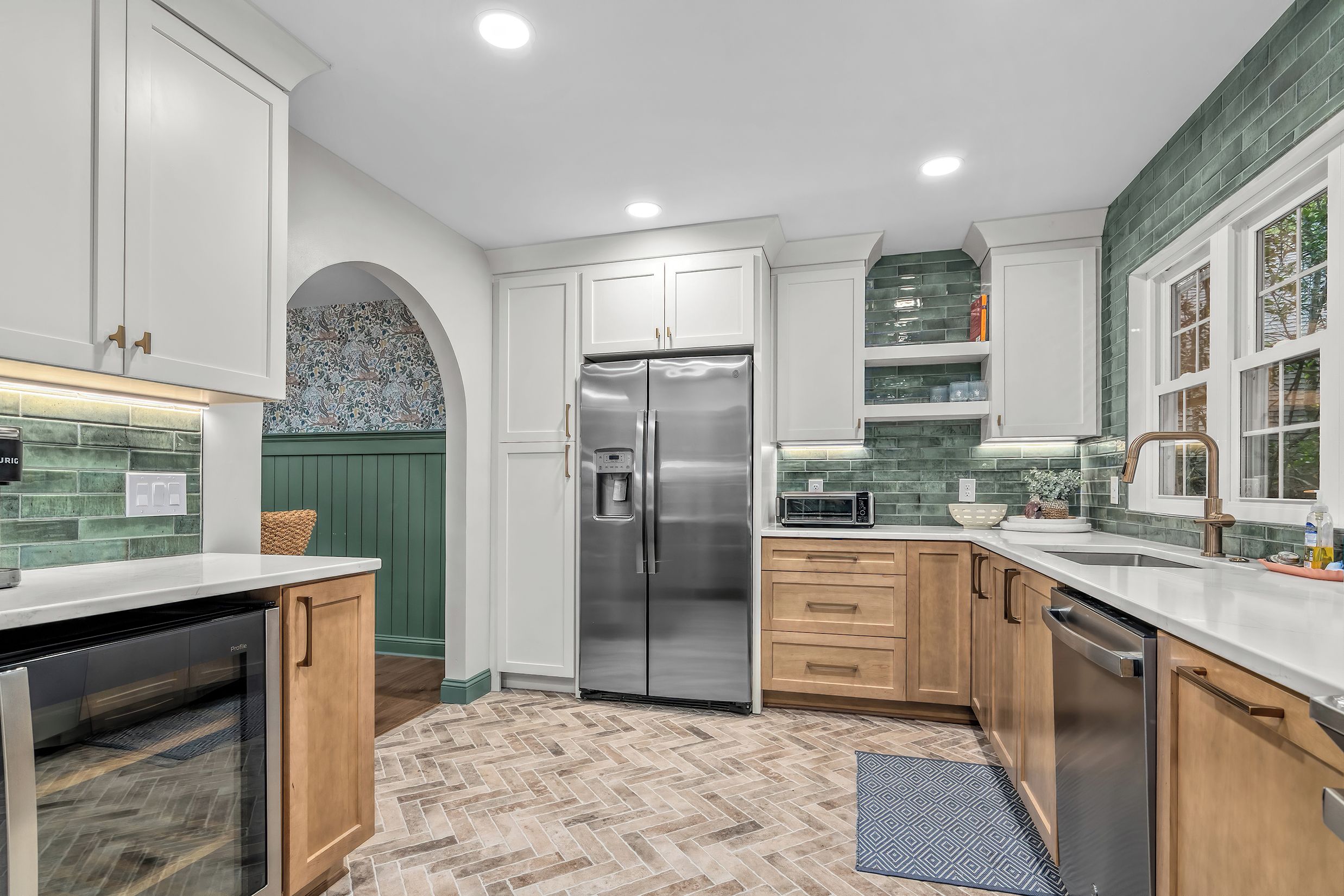 A modern kitchen with white cabinetry, a stainless steel refrigerator, a microwave, and a dishwasher.