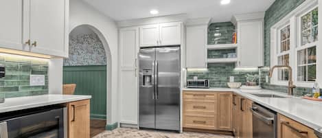 A modern kitchen with white cabinetry, a stainless steel refrigerator, a microwave, and a dishwasher.