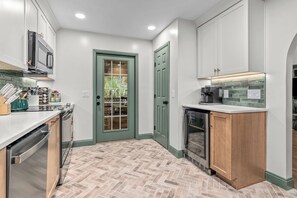 Una cocina moderna con piso de diseño espiga, electrodomésticos de acero inoxidable y una puerta verde.
