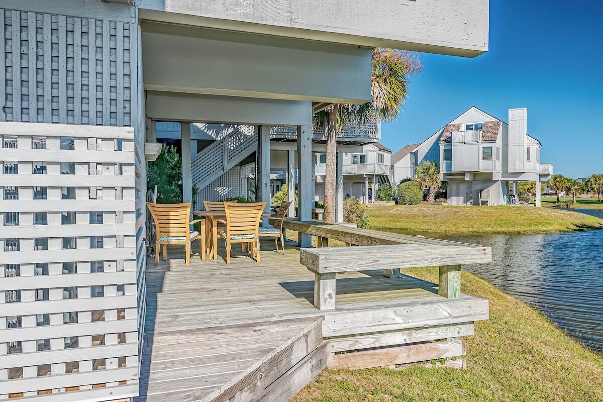 A waterfront property with a wooden deck, outdoor seating, and a view of the water.
