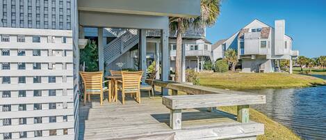 A waterfront property with a wooden deck, outdoor seating, and a view of the water.