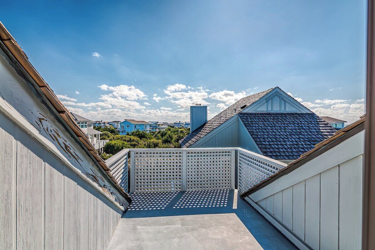 Une terrasse sur le toit offrant une vue sur les bâtiments environnants, un ciel dégagé et une rambarde en bois.
