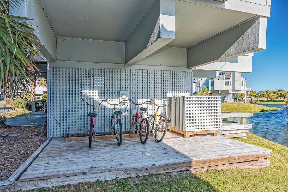 Un molo di legno con biciclette, una recinzione bianca e uno specchio d'acqua sullo sfondo.