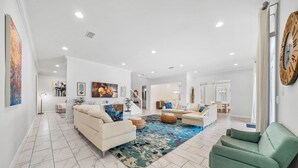 A spacious living room with a large rug, two sofas, and a green armchair. - 10Br Spacious Villa With Private Oversized Pool, Close To Disney (Davenport)