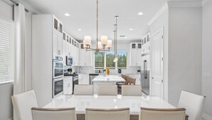 A modern kitchen with white cabinetry, a central island, and pendant lighting. - 10Br Spacious Villa With Private Oversized Pool, Close To Disney (Davenport)