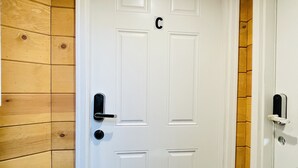 Una porta blanca amb una lletra 'C' a la part superior, un timbre i un estriau.