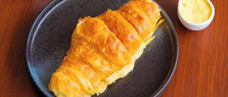 A plate with a pastry and a small bowl of sauce, and a plate with a folded pastry on a wooden table.