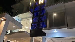 A modern building with a prominent illuminated sign reading "OMIZIO+". - Mzion Hotel Weligama (Weligama)