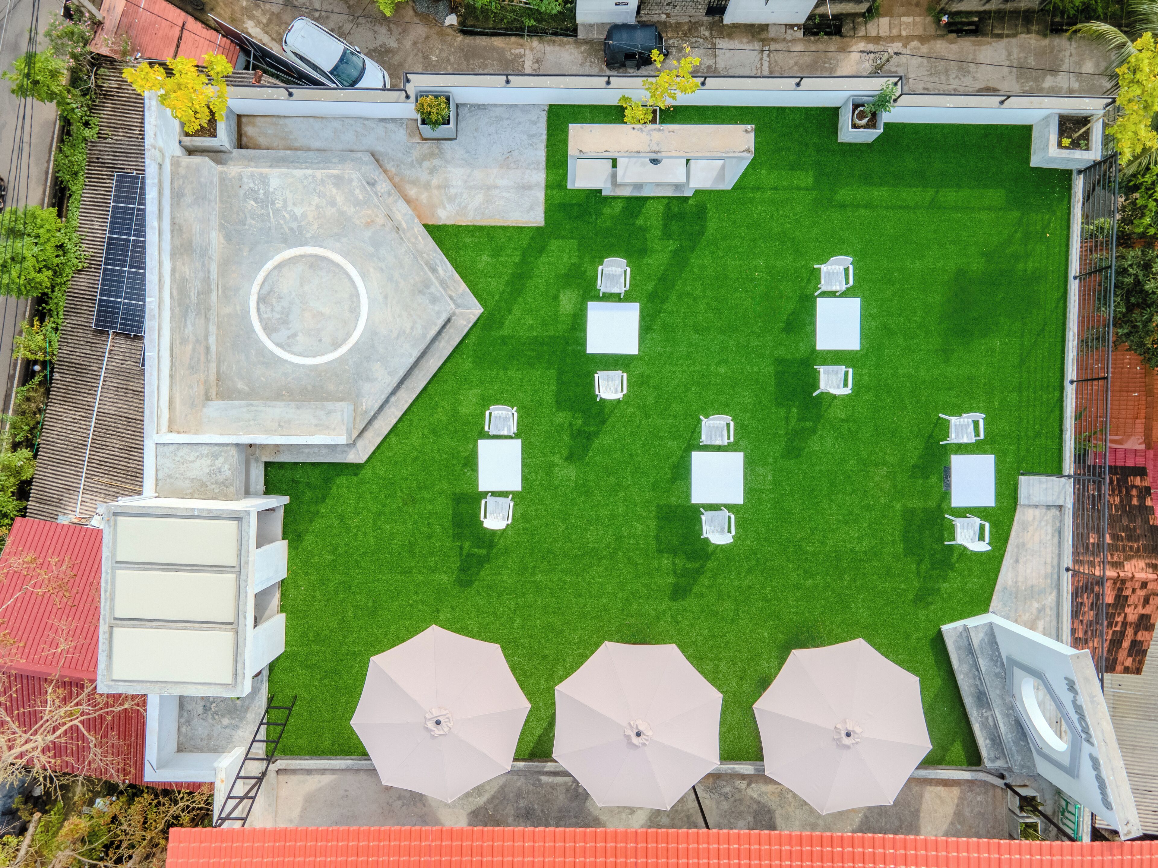 An aerial view of a rooftop garden with a seating area, solar panels, and a small pool.