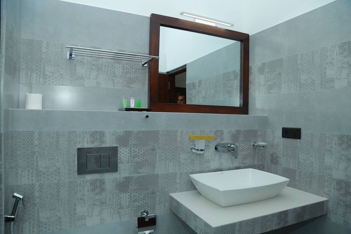 A modern bathroom with a large mirror, a white sink, and a shower.