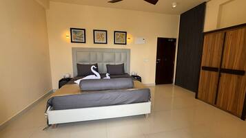 A bedroom with a bed, a ceiling fan, a door, and framed artwork on the wall.