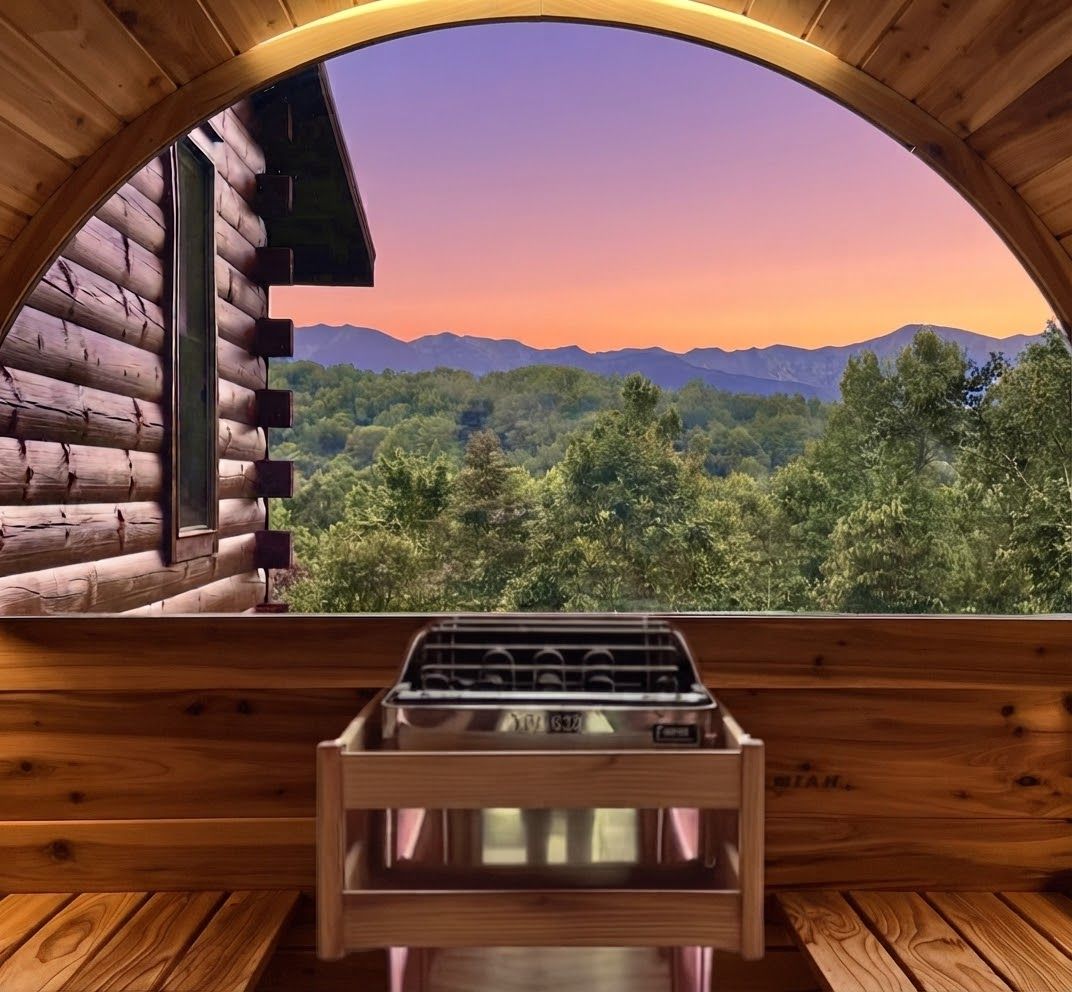 A wooden cabin with a large arched window overlooking a forested mountain range.