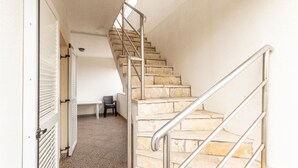 A staircase with metal railings leading to a landing area with a chair and a table.